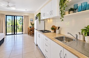 A modern kitchen with white cabinets, a stainless steel sink, and a wooden countertop. - Bay Breeze - Tropical Escape Horseshoe Bay Bowen (Bowen)