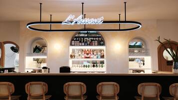 A bar area with a neon sign, shelves of liquor bottles, and wooden chairs.