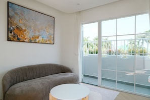 A modern living room with a grey sofa, a round white table, and a large abstract painting on the wall.