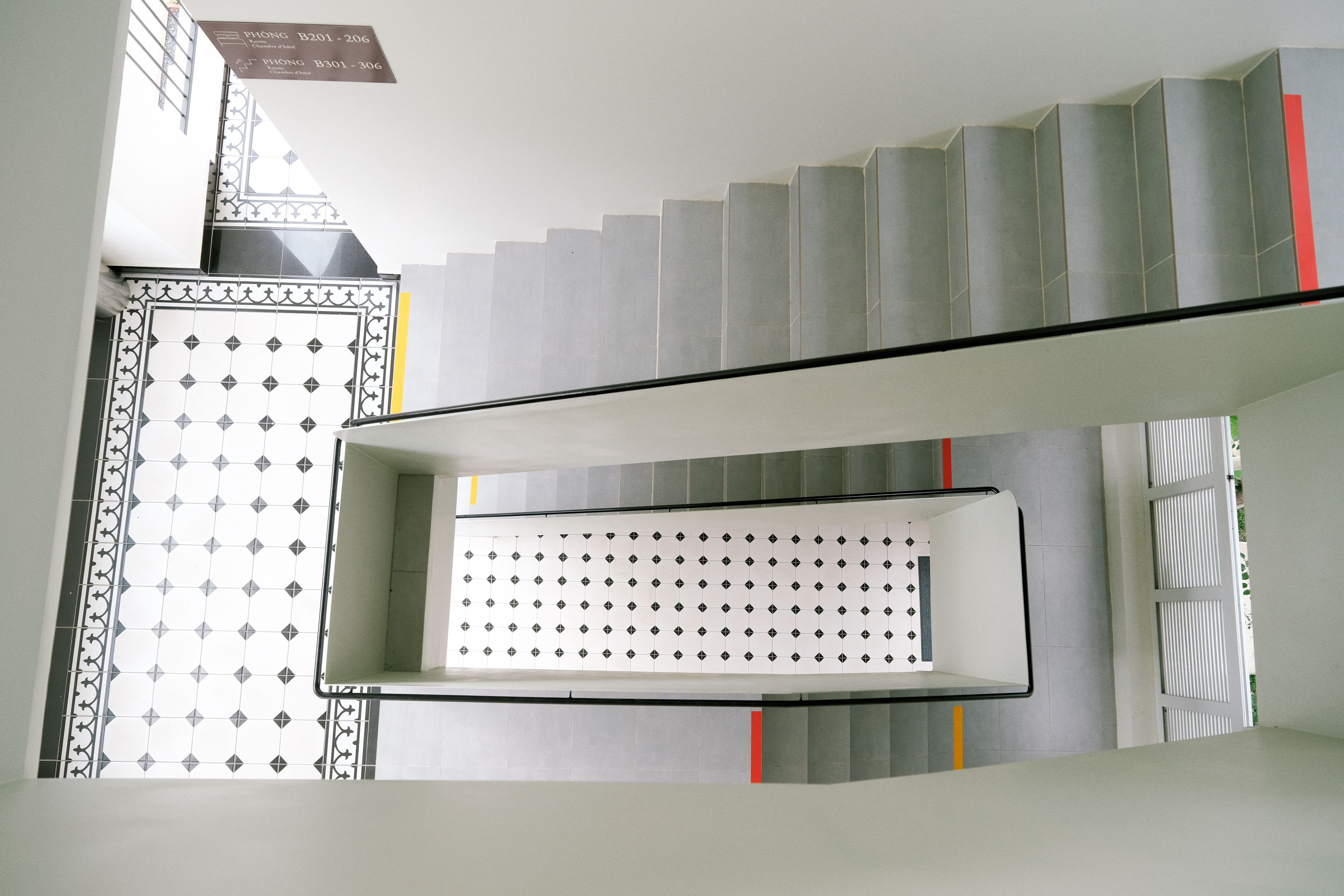 A staircase with a patterned wall and a sign indicating hotel room numbers.