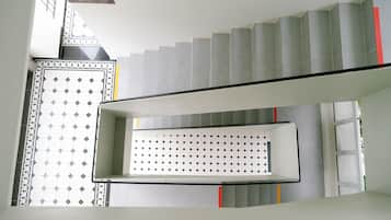 A staircase with a patterned wall and a sign indicating hotel room numbers.