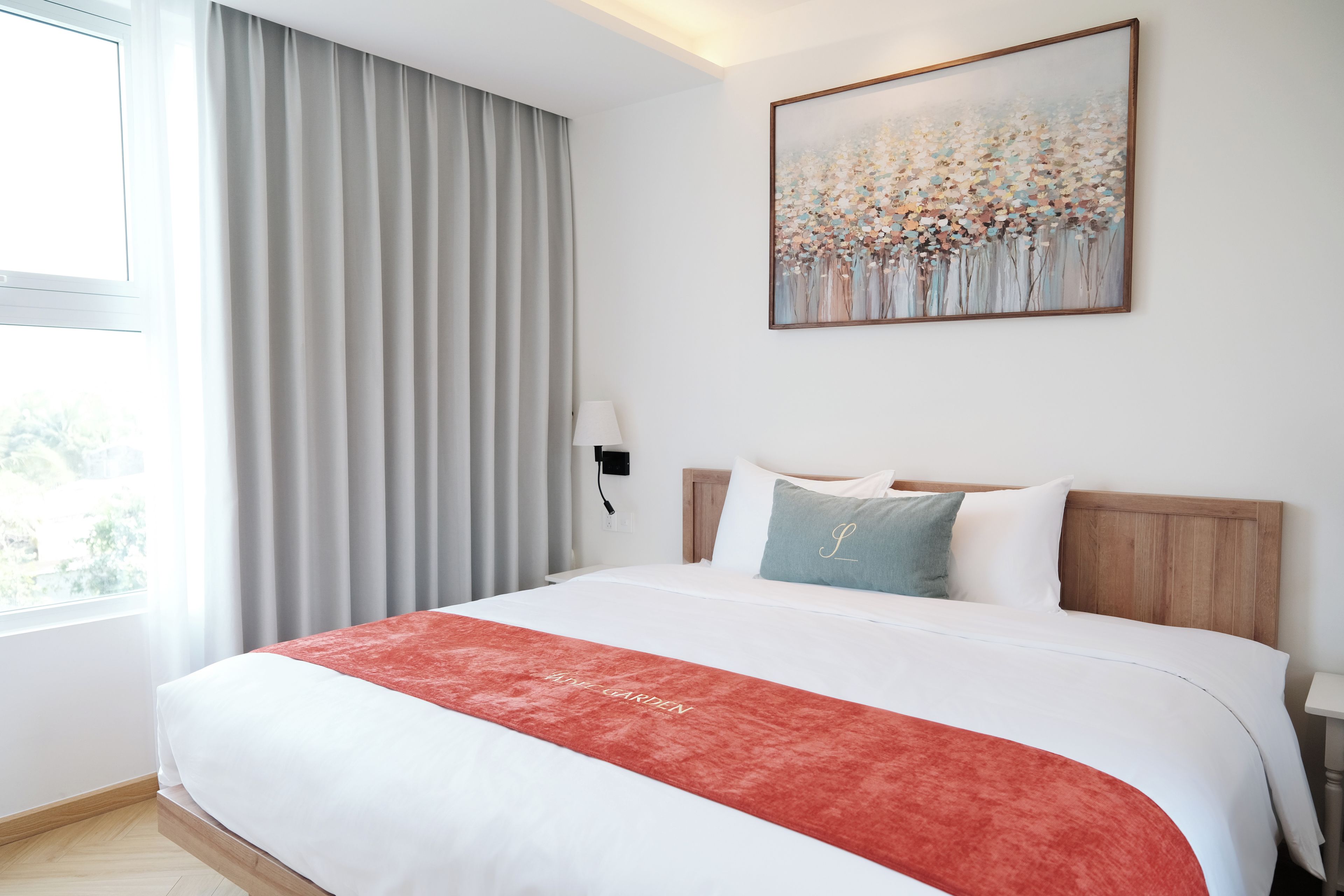 Een hotelkamer met een groot bed, een schilderij aan de muur en een raam met gordijnen.