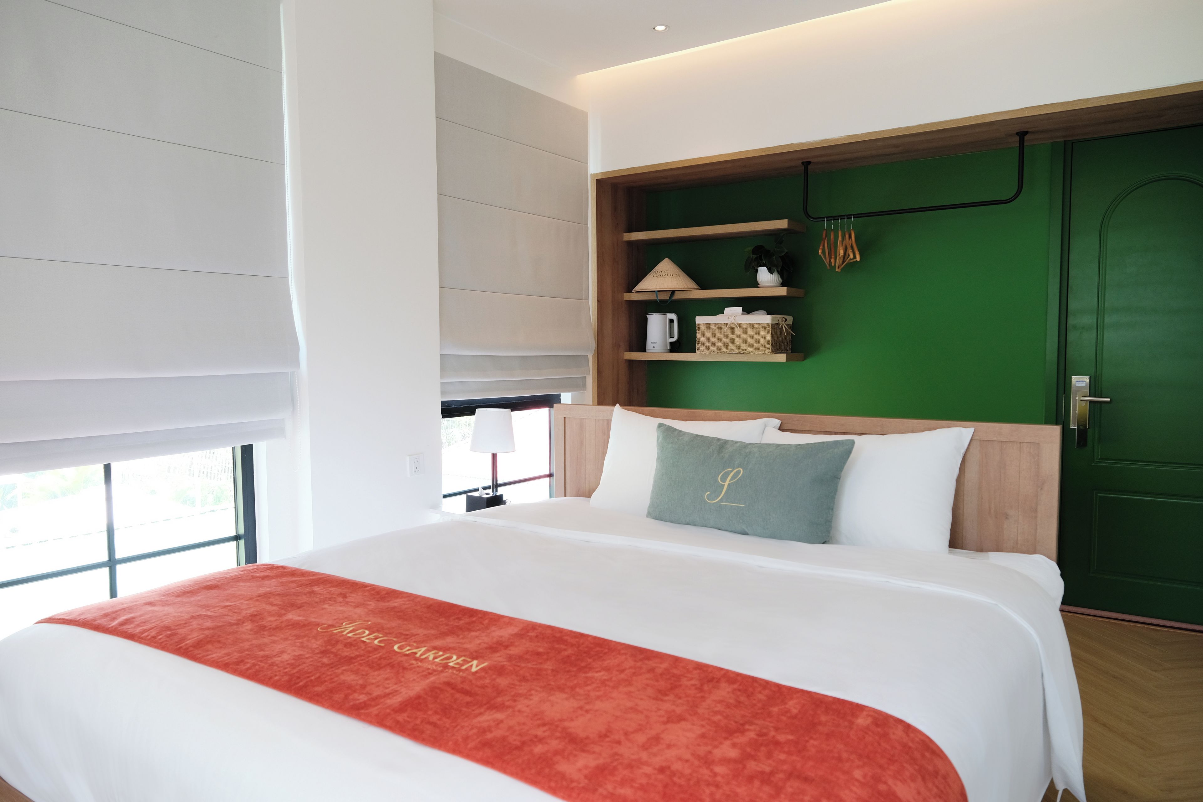 Una habitación de hotel moderna con una cama grande, una pared de acento verde y un cabecero de madera.