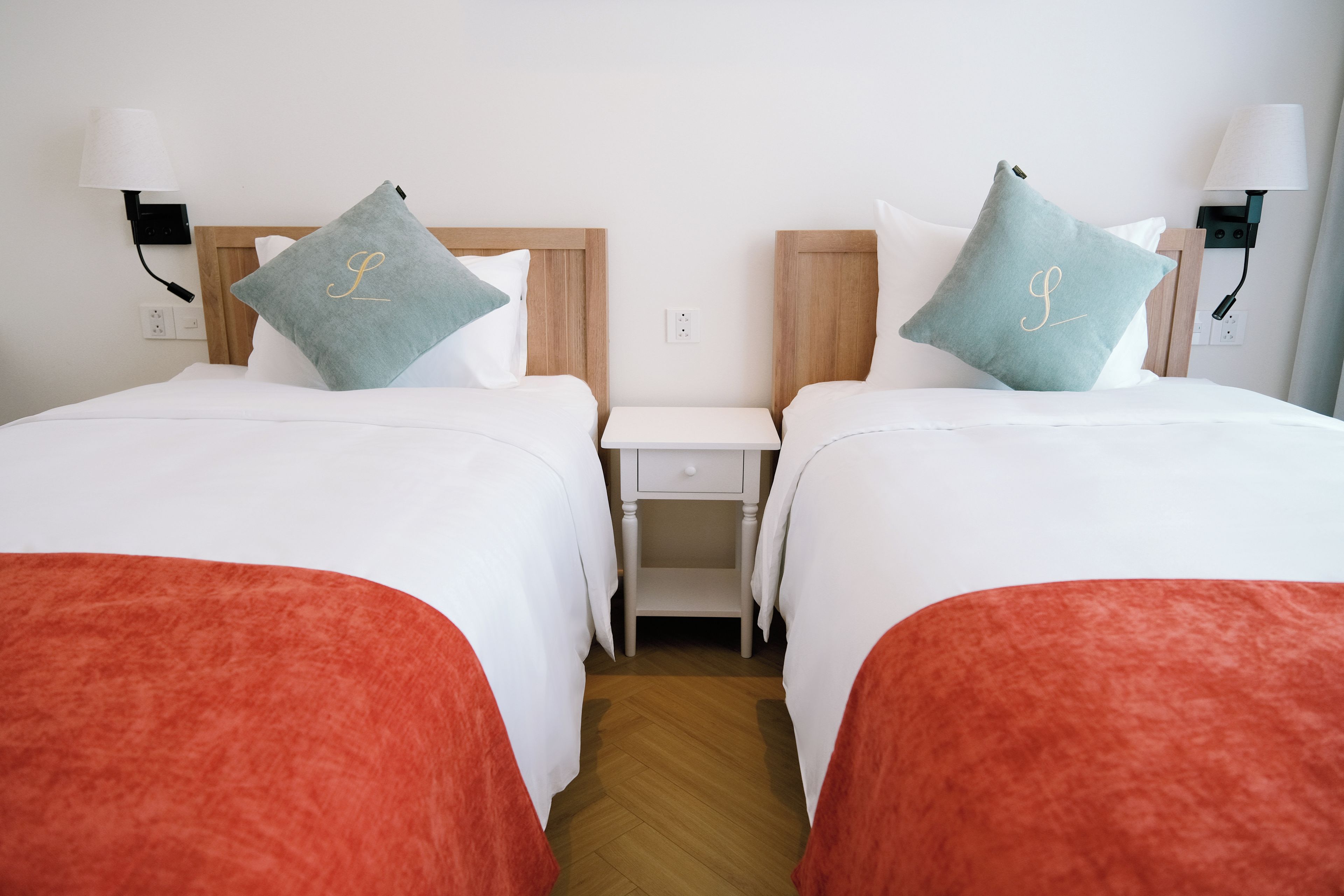 Une chambre d’hôtel avec deux lits, chacun étant agrémenté d’un oreiller orné d’un monogramme.