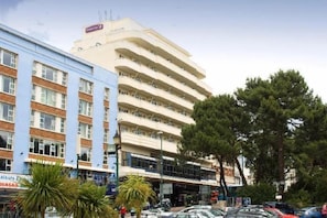 A multi-story building with a flat facade, several balconies, and a parking area in front. - Bournemouth Central (Bournemouth)