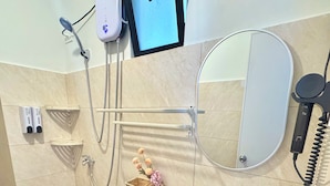 Une salle de bain équipée d’un WC, d’un bidet, d’un lavabo, d’un miroir et d’une pomme de douche.