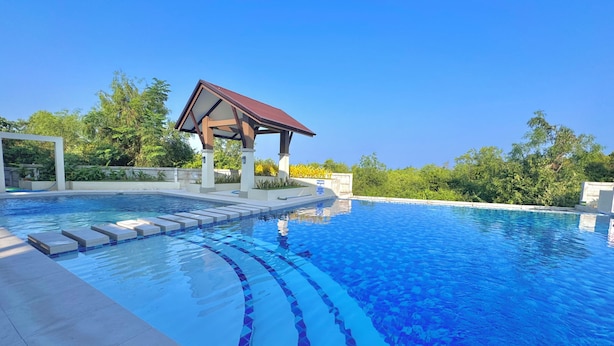 Une piscine d’un bleu éclatant, dotée d’un pavillon et de marches menant à l’eau.