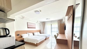 Une chambre d’hôtel équipée d’une kitchenette, d’un lit, d’un bureau et d’une grande fenêtre.