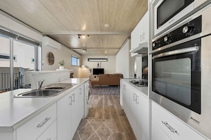 A compact kitchen with built-in appliances, a central island, and a seating area in the background.