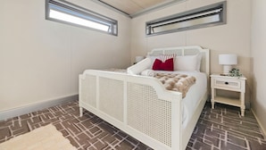 Una camera da letto con un letto bianco, un comodino, una finestra e un pavimento decorato.