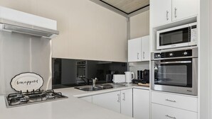 A modern kitchen with white cabinetry, a gas stove, a microwave, and an oven.