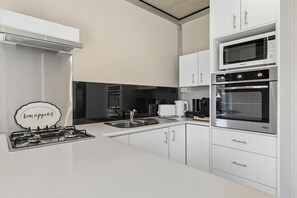 A modern kitchen with white cabinetry, a gas stove, a microwave, and an oven.