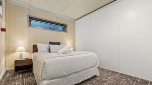 A hotel room with a bed, a nightstand, a lamp, a window, and a patterned carpet.