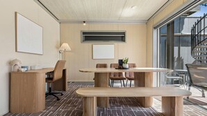 A modern meeting room with a wooden table, chairs, a bench, and a large window.