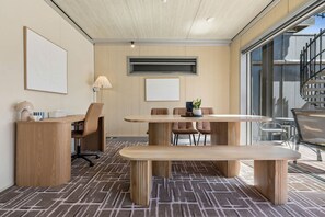 A modern meeting room with a wooden table, chairs, a bench, and a large window.