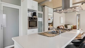 Eine moderne Küche mit Kochinsel, Backofen und Essbereich mit Sofa und Stühlen.