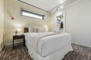 A hotel room with a bed, bedside table, lamp, and a window with blinds. - 2BR Unit For 5, Kangaroo Flat (Kangaroo Flat)