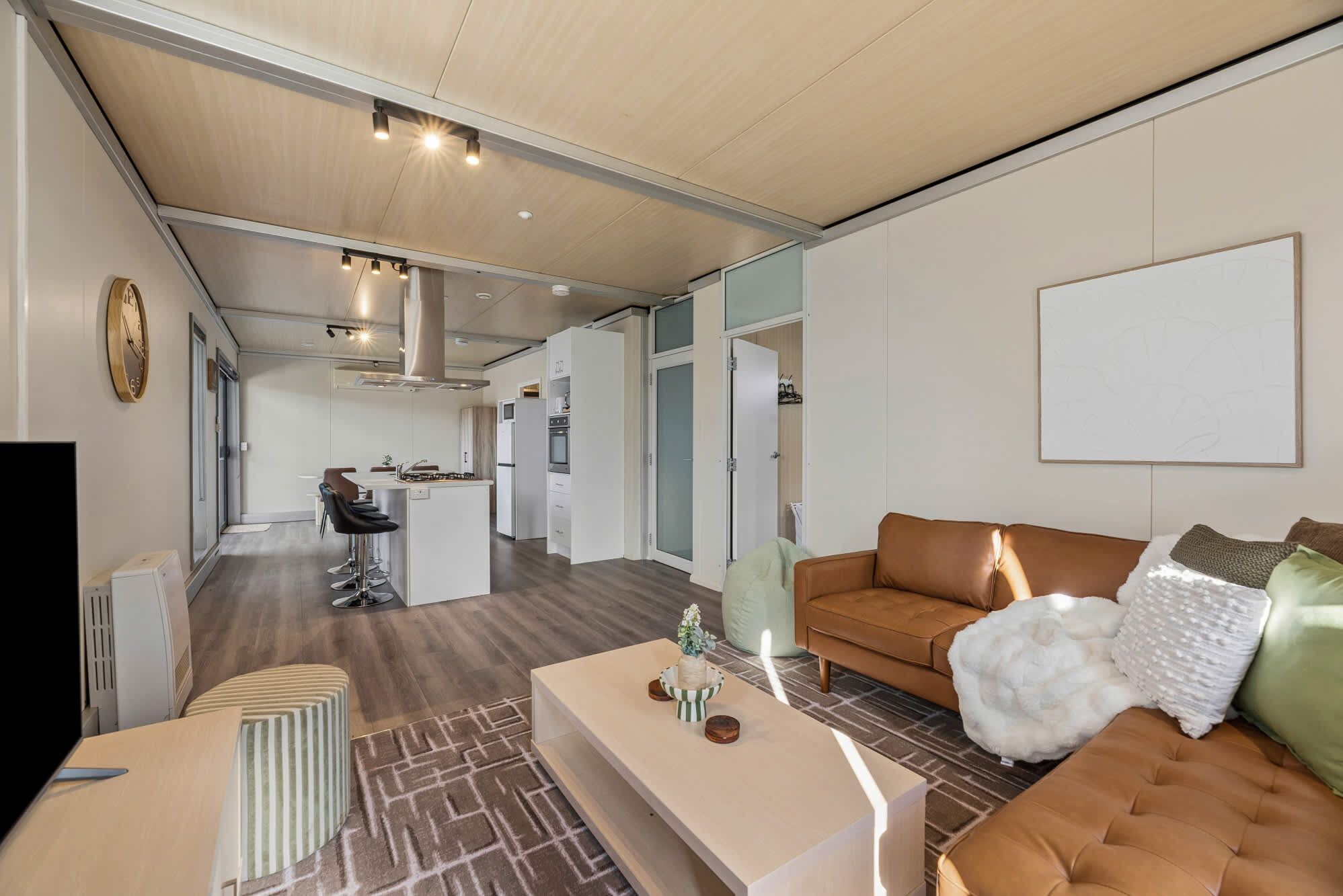 Una sala moderna con sofá, mesa de centro y televisor. Cuenta con una zona de cocina con mesa y sillas.