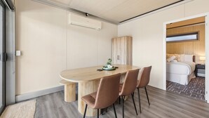 Ein modernes Hotelzimmer mit einem Holztisch, vier Stühlen, einem Holzschrank und einem Bett mit einem Holzvorhang.