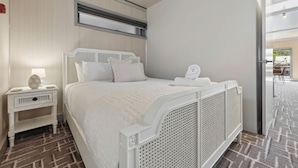 Ein Hotelzimmer mit Bett, Nachttisch, Lampe und Blick ins Freie.