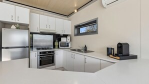 A compact kitchen with white cabinets, a stainless steel stove, a microwave, and a coffee machine. - Cosy 2BR Kangaroo Flat Unit (Kangaroo Flat)