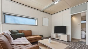A modern living room with a leather sofa, a flat-screen TV, and a minimalist design. - Cosy 2BR Kangaroo Flat Unit (Kangaroo Flat)