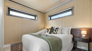 A hotel room with a bed, bedside tables, a lamp, and two windows. - Cosy 2BR Kangaroo Flat Unit (Kangaroo Flat)