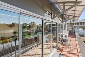 Apartament modern amb portes de vidre grans, un pati amb mobles d'exterior i vista de la zona circumdant.