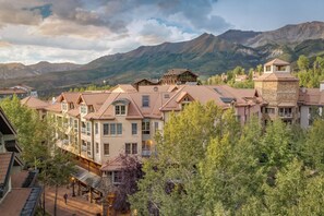 A mountain resort with multiple buildings, including a lodge with a stone facade and a wooden structure. - Cozy 1BR Mountain Village Palmyra Condo with Fireplace and Ski Views (Telluride)
