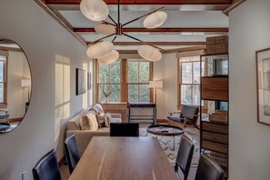 A dining area with a wooden table, chairs, a sofa, and a ceiling fan. - Cozy 1BR Mountain Village Palmyra Condo with Fireplace and Ski Views (Telluride)