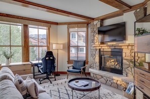 A cozy living room with a fireplace, comfortable seating, and large windows offering a view of the outside. - Cozy 1BR Mountain Village Palmyra Condo with Fireplace and Ski Views (Telluride)
