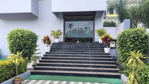 A set of outdoor stairs leading to a building entrance, surrounded by potted plants and a patterned pavement. - Deluxe Gran-villa (Lalbag)
