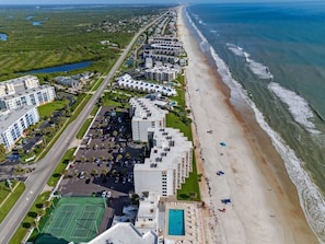 An aerial view of a coastal hotel with a beach, tennis courts, and a swimming pool. - Direct Oceanfront Condo in New Smyrna Beach on No-Drive Beach, 2B2B (New Smyrna Beach)