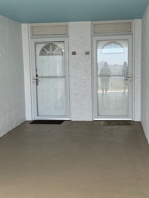 A room with two white doors, a concrete floor, and a textured wall.