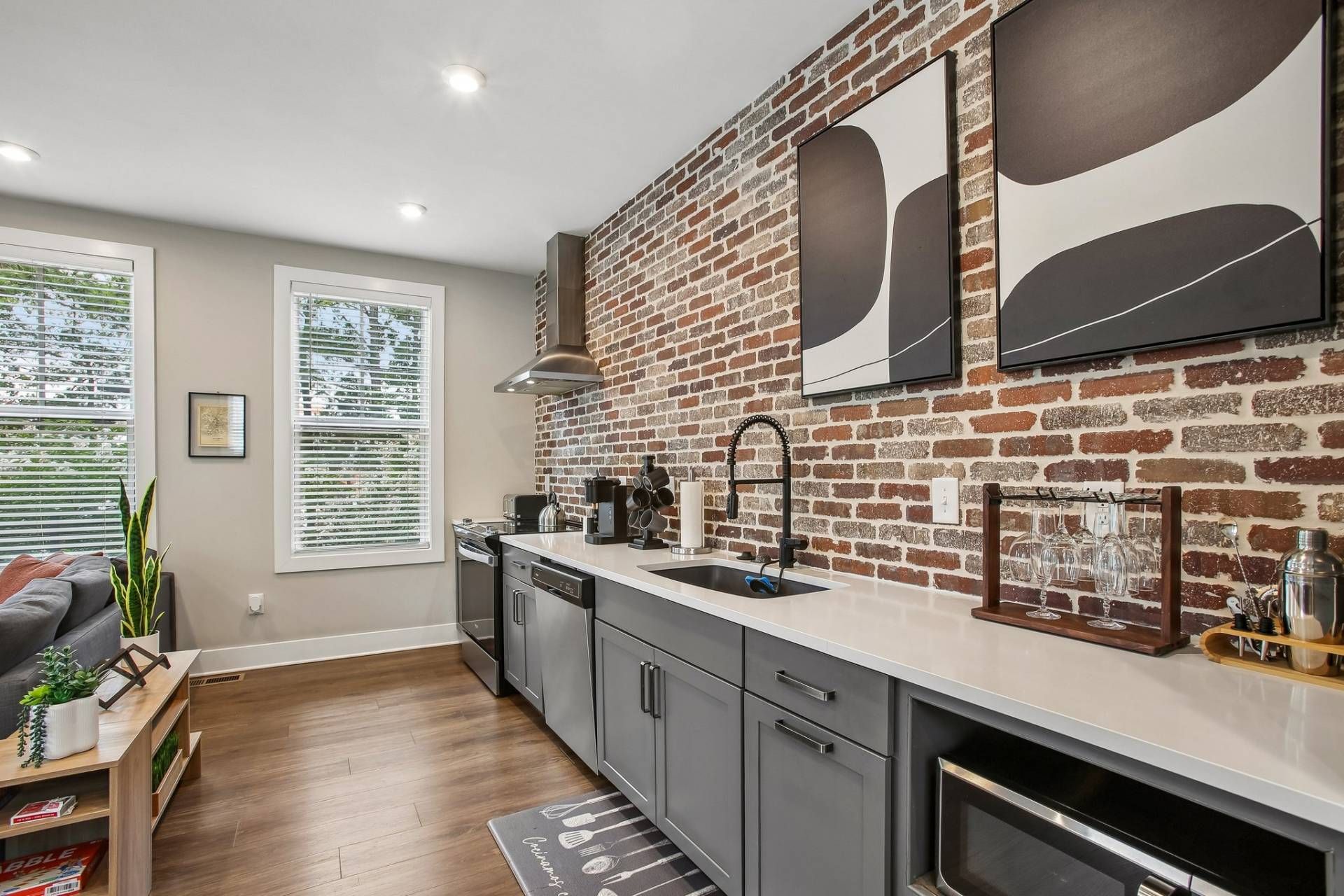 A modern kitchen with a brick wall, stainless steel appliances, and a built-in oven.