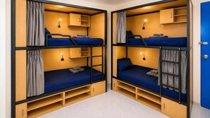 Una habitación con dos literas, cada una con un escritorio y un estante pequeño, y un armario.