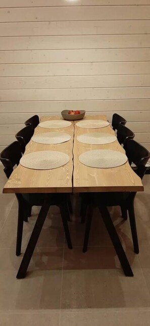 Een rechthoekige eettafel met vier stoelen, een kom in het midden en placematen.