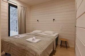 A bedroom with a bed, pillows, a small table, and a window with curtains.
