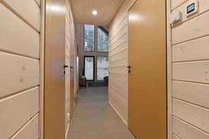 Een gang met houten deuren en zicht op een besneeerd landschap door grote ramen.