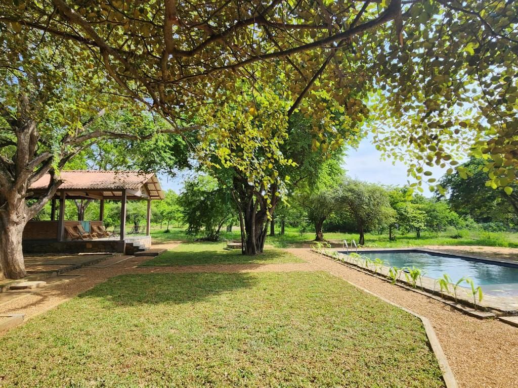 A pool area with a gazebo, trees, and a well-maintained lawn.