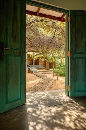 An open door leading to a covered outdoor area with a stone pathway and a bench.