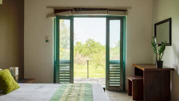 Une chambre à coucher avec un lit, un bureau et une vue sur l’extérieur, grâce à des volets ouverts.