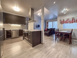 A modern kitchen with stainless steel appliances, a central island, and a dining area with a table and chairs. - Ruka nature: sauna, WiFi, cleaning incl. (Kuusamo)