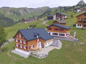 A cluster of chalet-style buildings with sloped roofs, surrounded by green hills and a mountain in the background. - Holiday Home in Damuls With Swimming Pool (Damüls)