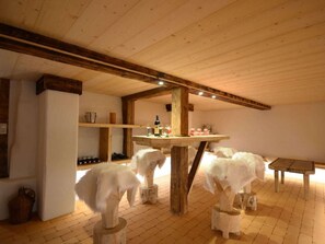 A rustic room with a wooden table, two white animal sculptures, a bench, and a brick floor. - Holiday Home in Damuls With Swimming Pool (Damüls)