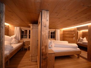A wooden cabin with three bunk beds, each with white bedding and pillows. - Holiday Home in Damuls With Swimming Pool (Damüls)