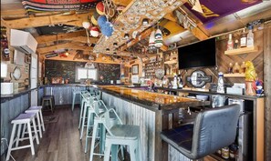 A bar area with a counter, stools, and a television screen. - Sea Breeze Cottage | The Inn on Turville Creek (Berlin)