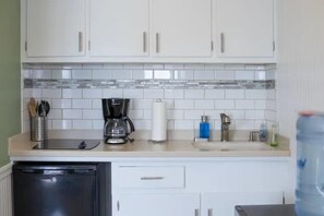 A kitchen with white cabinets, a coffee maker, a roll of paper towels, and a dish rack.
