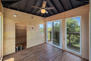 A spacious room with a high ceiling, a ceiling fan, and large windows offering a view of trees. - Free Ruby Falls Ticket & More-Hot Tub-Handcrafted Cabin with Tower-Lookout Mountain-Romantic Getaway (Lookout Mountain)