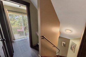 Eine Treppe führt zu einem Balkon mit Blick auf viel Grün.